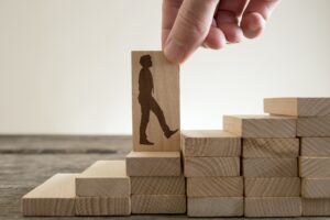 Man holding with his fingers wooden domino with shape of busines
