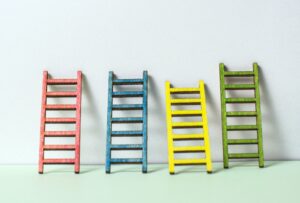 Multicoloured ladders on wall. Pastel tones. Concept for success and growth.
