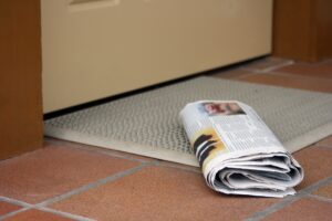 Daily newspaper waiting to be picked up outside home entrance door
