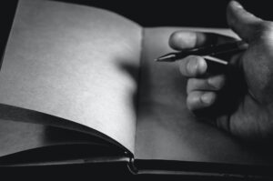 Empty pages of a notebook and a hand holding a pen