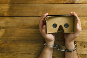 Hands in shackles grabbing some virtual reality glasses.