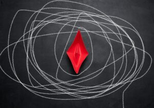 Red paper boat on a black chalkboard and a long drawn path in white chalk.