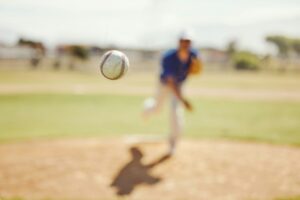 Sports, pitch and baseball ball in air, pitcher throwing it in match, game or practice in outdoor f