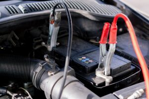 close-up At a service station a battery in a car with tongs connected for charging the battery