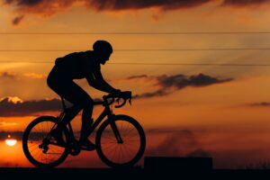 Silhouette of man cycling on road during sunset