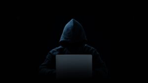 Hacker in a hood on a dark background, IT specialist.Concept of Data thief, internet fraud.