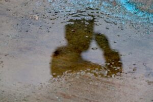 Shadow of saluting soldier on iced sidewalk covered in salt melt.