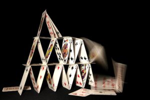 House of cards collapsing on dark backgroun